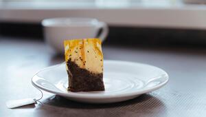 Ein aufgebrühter Teebeutel steht aufrecht auf einem Unterteller.