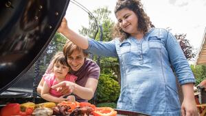 Eltern stehen mit ihrer Tochter vor einem Grill