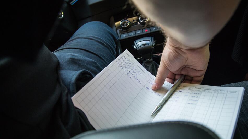 Ein Mann führt ein Fahrtenbuch im Auto