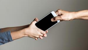 Kind klammert sich an ein Smartphone, das eine erwachsene Person aus der Hand nehmen möchte