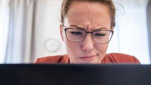 Eine Frau verzieht das Gesicht vor einem Laptop