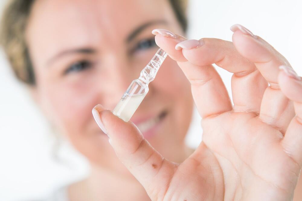 Frau hält ein Serum zur gesichtspflege in der Hand