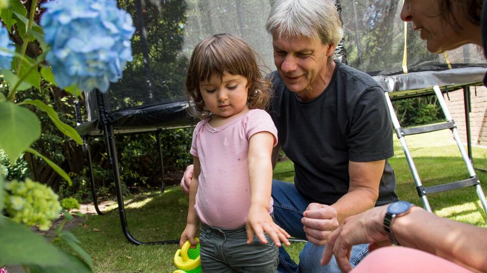 Großeltern spielen mit ihrer Enkelin im Garten