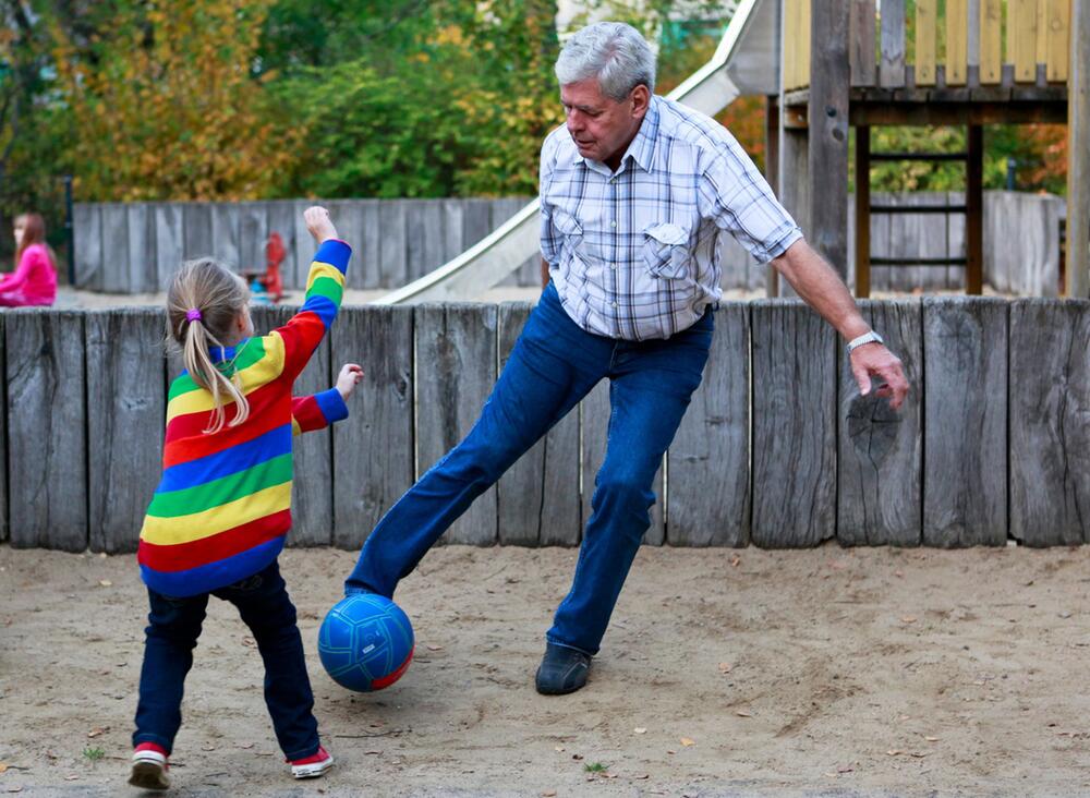 Ein Großvater spielt mit seinem Enkelkind Ball
