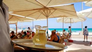 Ein Kellner serviert an einem mallorquinischen Strand einen Wein