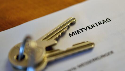 Schlüssel und Mietvertrag liegen auf einem Holztisch