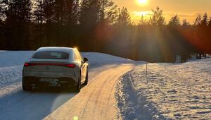 Auto fährt bei tiefstehender Sonne über eine verschneite Straße