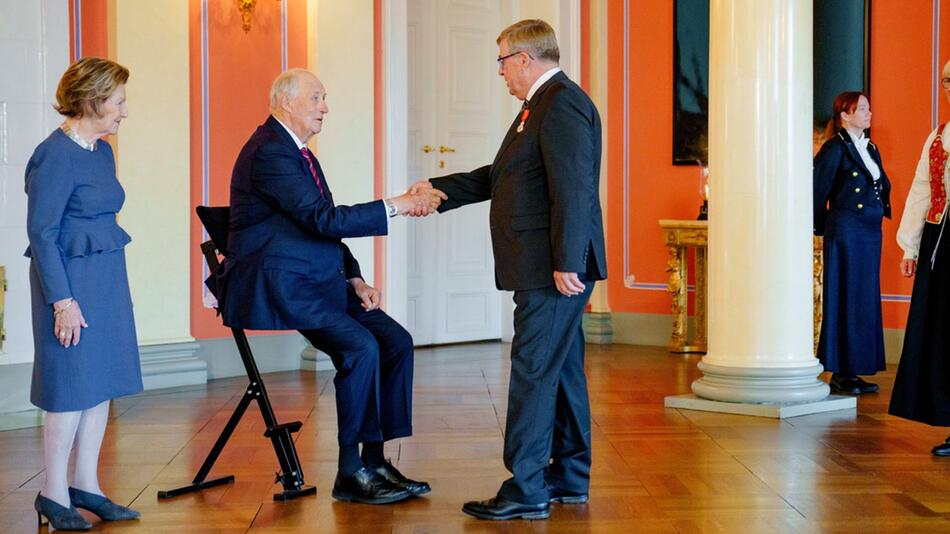 König Harald empfängt Besucher im Sitzen.