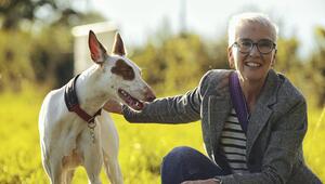 Eine Frau ist in der Hocke und streichelt einen weißen Hund mit braunem Fleck ums Auge.