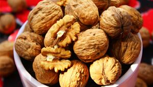 Eine weiße Schale gefüllt mit ganzen Walnüssen in der Schale und zwei aufgebrochenen ...