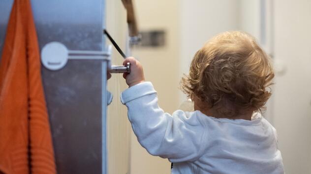 Ein Kind hält sich an einem Schrank mit Sicherung fest