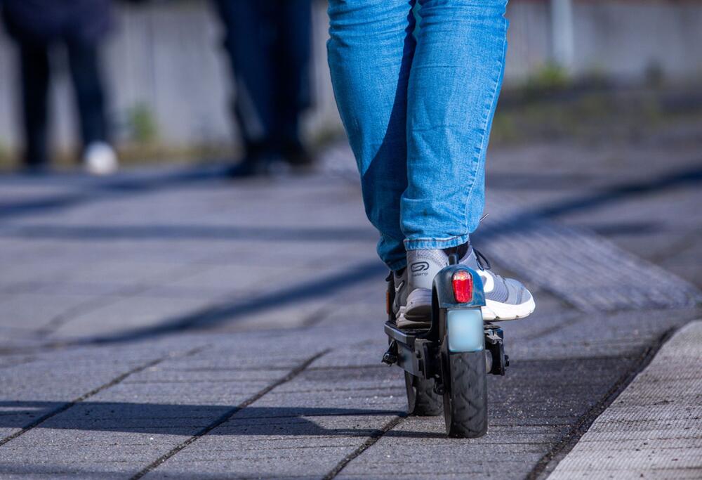 Ein Reisender fährt mit seinem E-Scooter über den Bahnsteig.
