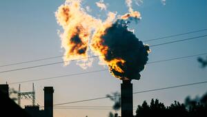 Rauchwolke, die von einem Schornstein eines Gaskraftwerks aufsteigt, beleuchtet vom Sonnenlicht