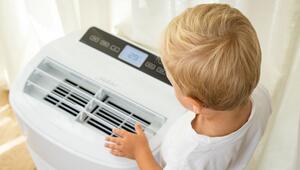 Junge steht vor einer Klimaanlage