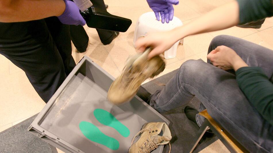 Eine Frau zieht ihre Schuhe bei einer Sicherheitskontrolle aus