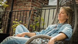 Frau sitzt entspannt im Hängesessel auf einer Terrasse