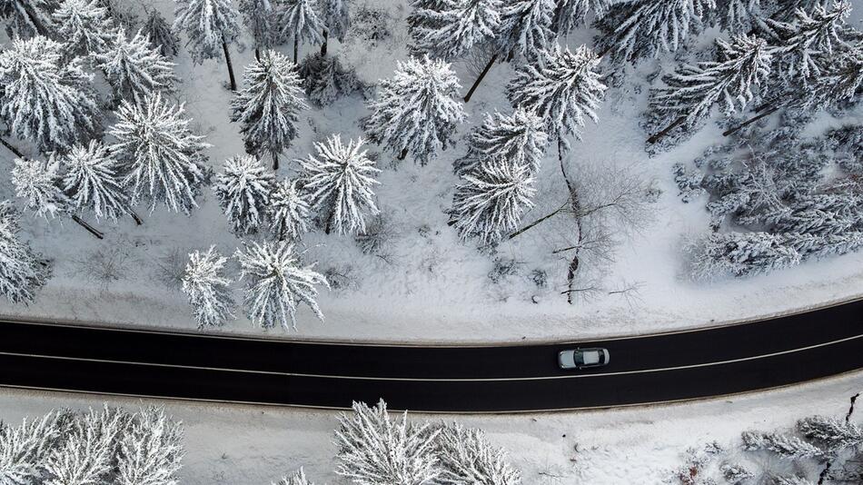 Auto fährt durch Winterlandschaft