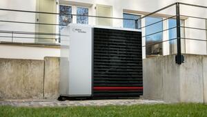 Außen aufgestellte Wärmepumpe der Marke alpha innotec vor einem weißen Haus mit Fenstern und ...