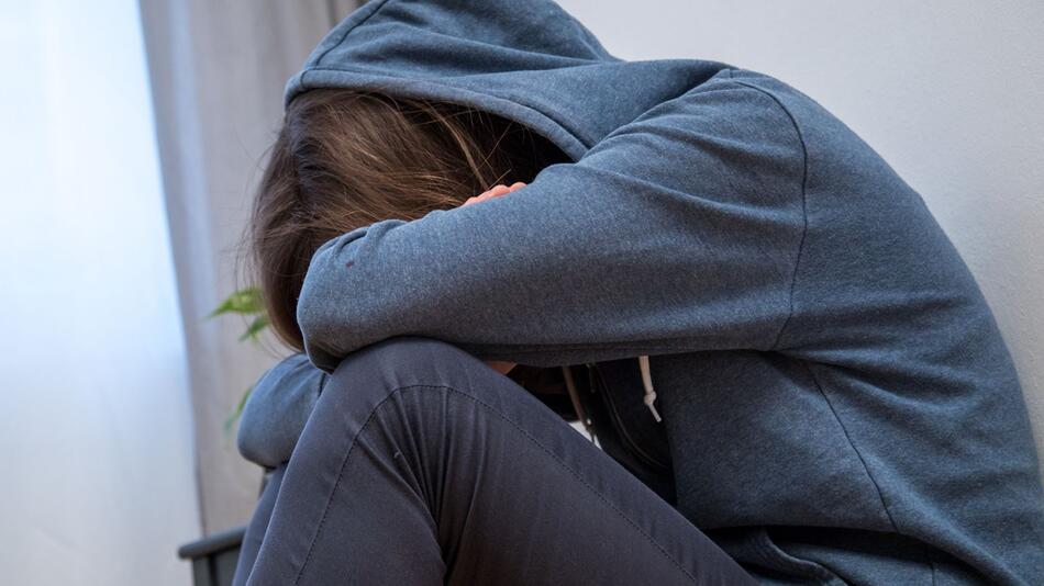 Traurige Frau sitzt am Boden