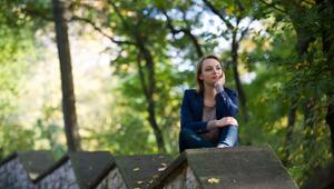 Eine Frau sitzt nachdenklich auf einer Mauer im Park