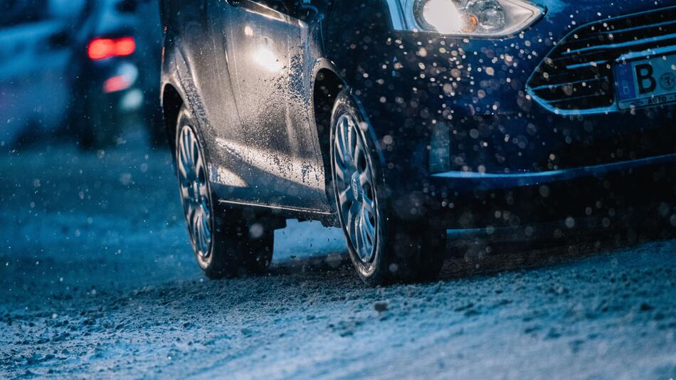 Ein Auto fährt zur dunklen Jahreszeit auf der Straße