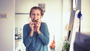 Frau isst Gurke und Schokolade