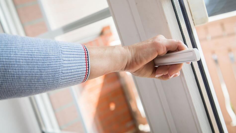 Eine Frau öffnet ein Fenster
