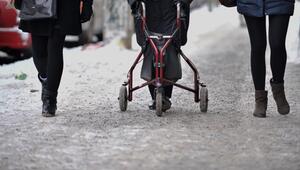 Ein Frau geht mit Rollator auf einem schneebedeckten Gehweg