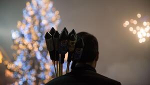 Ein Mann mit Feuerwerksraketen vor einem Weihnachtsbaum