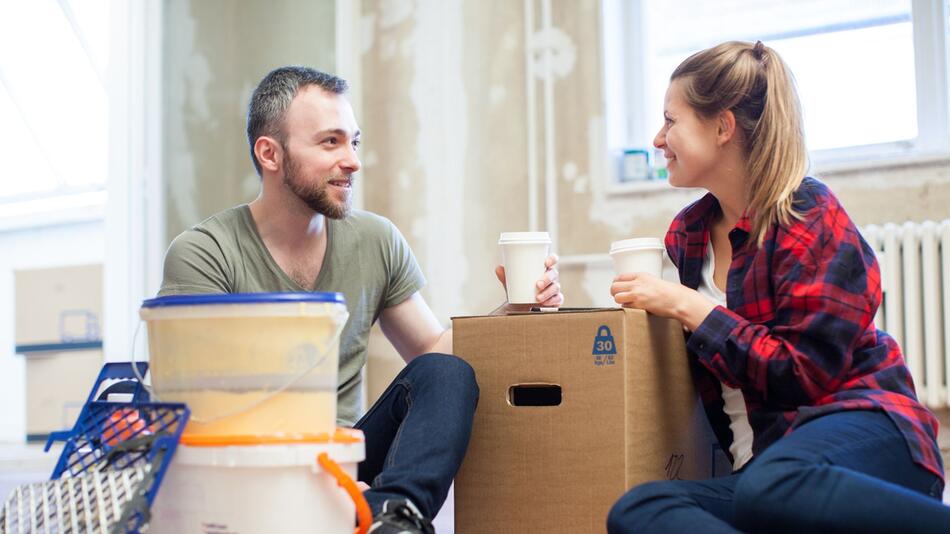 Paar sitzt mit Umzugkisten in einer Wohnung