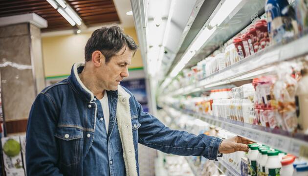Mann in Supermarkt, der Preise vergleicht. 