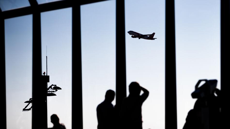 Passagiere schauen am Flughafen einem startenden Flugzeug zu