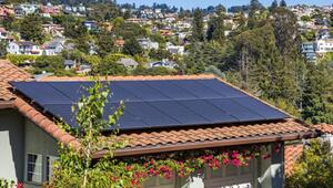 Solarmodule auf einem roten Ziegeldach eines Hauses, umgeben von grünen Bäumen