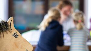 Ein Elternteil sitzt mit seinen Kindern an einem Tisch