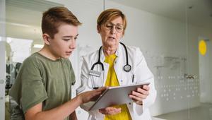 Ärztin schaut mit einem Jungen auf ein Tablet