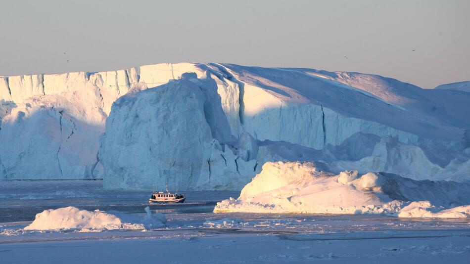 Schiff mit Touristen fährt im Ilulissat-Eisfjord vor Eisbergen