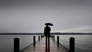 Ein Mann steht mit einem Regenschirm auf einem Steg