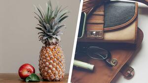 Links eine Ananas, ein roter Apfel und ein grünes Blatt auf einem Holztisch vor beigem ...