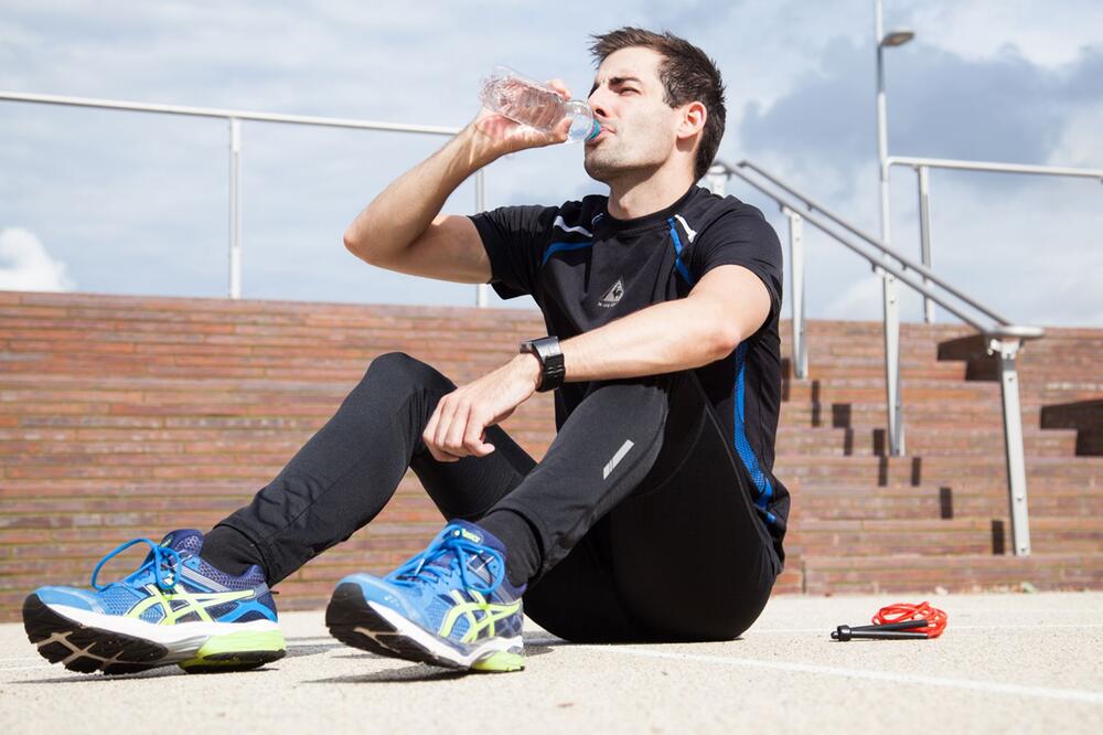 Mann trinkt Wasser bei Sportpause