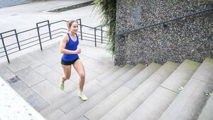 Frau joggt im Park die Stufen einer Treppe empor