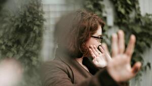 Frau mit braunen Haaren und Brille, die seitlich steht und ihre Hand mit ausgestreckten Fingern ...