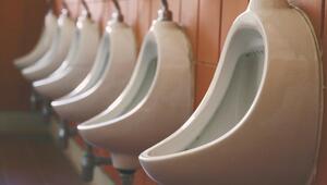 Pissoirs an einer orangen Fliesenwand. 