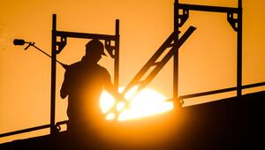 Ein Bauarbeiter im Gegenlicht der Sonne auf einem Gerüst