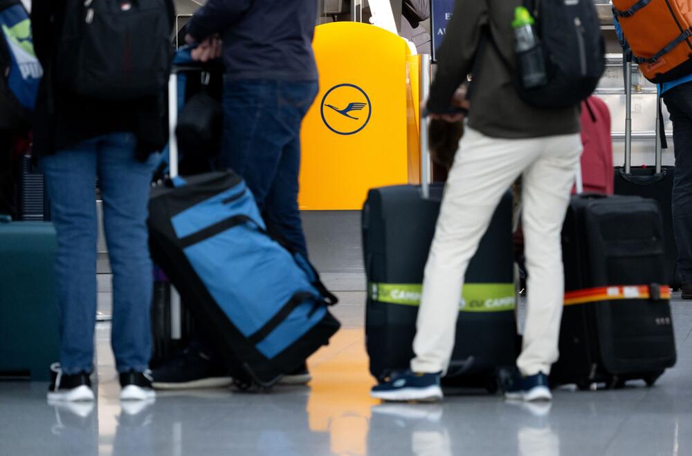 Passagiere warten an einem Check-In-Schalter der Lufthansa