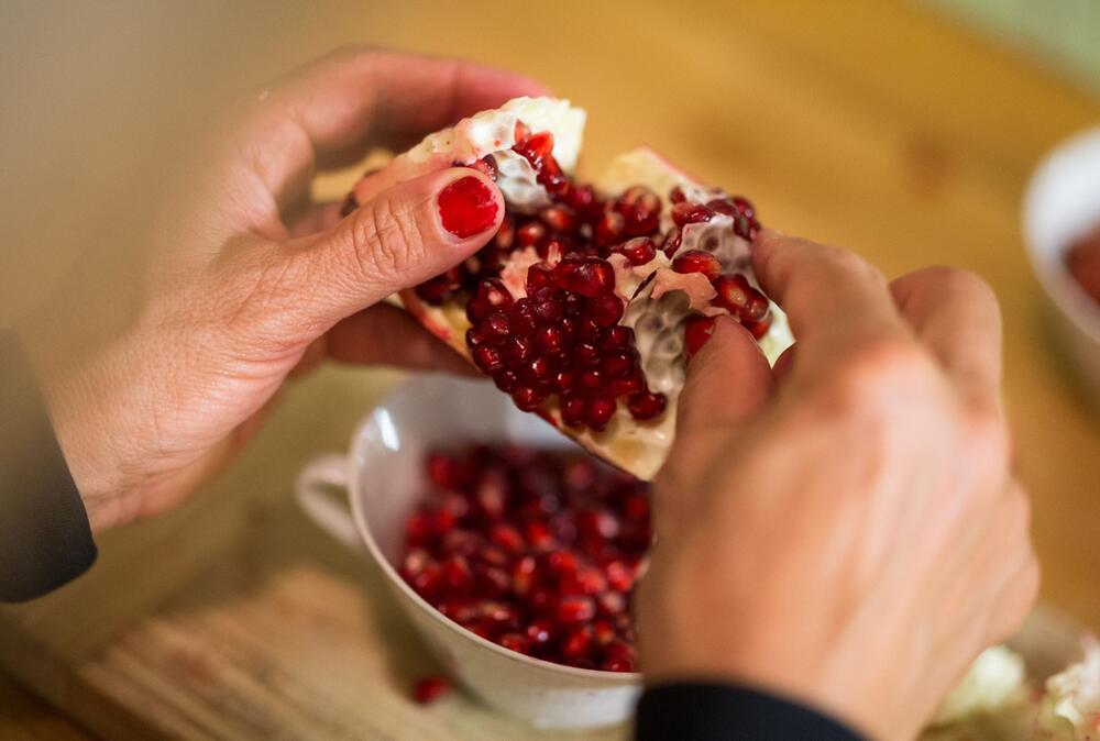 Frau schält einen Granatapfel
