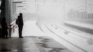 Mann steht am verschneiten Bahngleis