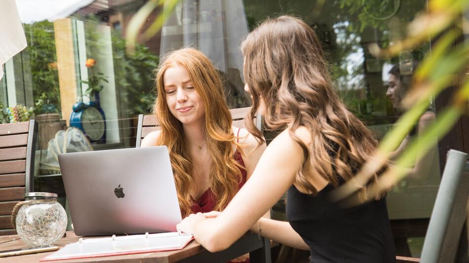 Zwei Mädchen sitzen vor einem Laptop