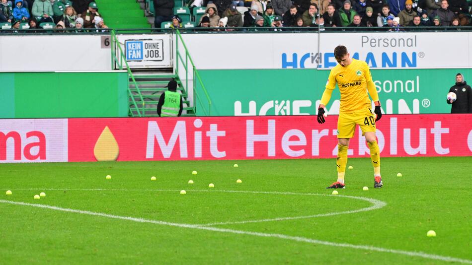 Jonas Urbig (SpVgg Greuther Fürth) steht auf einem Platz mit Tennisbällen.