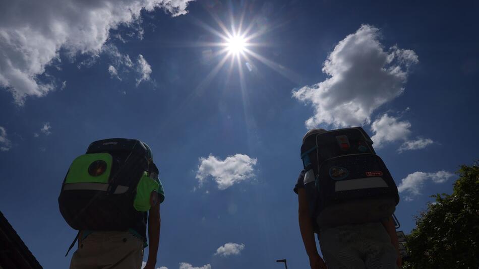 Zwei Schüler mit Ranzen laufen im Sonnenschein