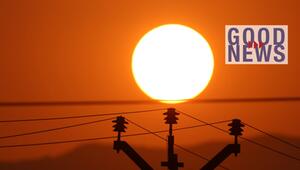 Die untergehende Sonne am orangefarbenen Himmel hinter einer Silhouette von Stromleitungen und ...